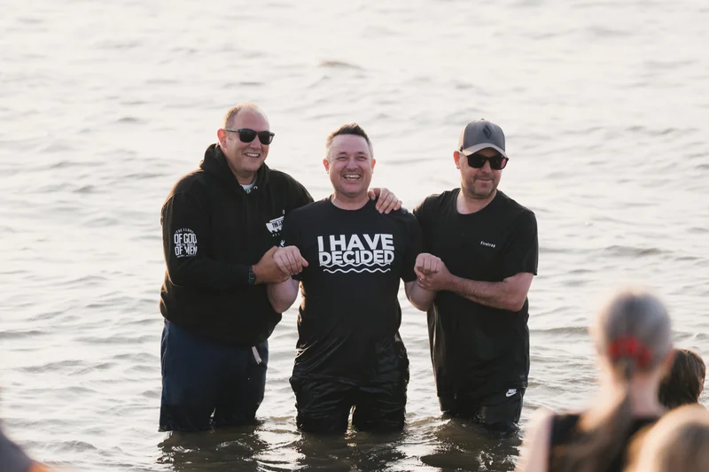 a group of men standing in the water with a sign that says have a good day