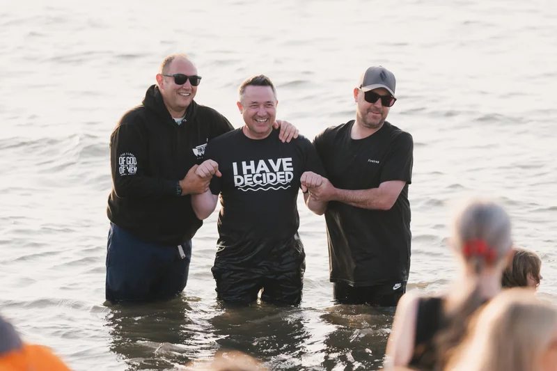 a group of men and women standing in the water