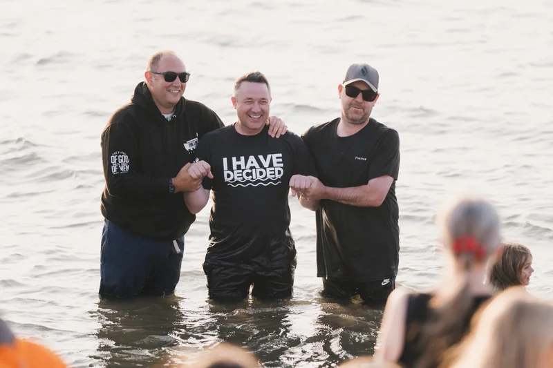 a group of men and women standing in the water