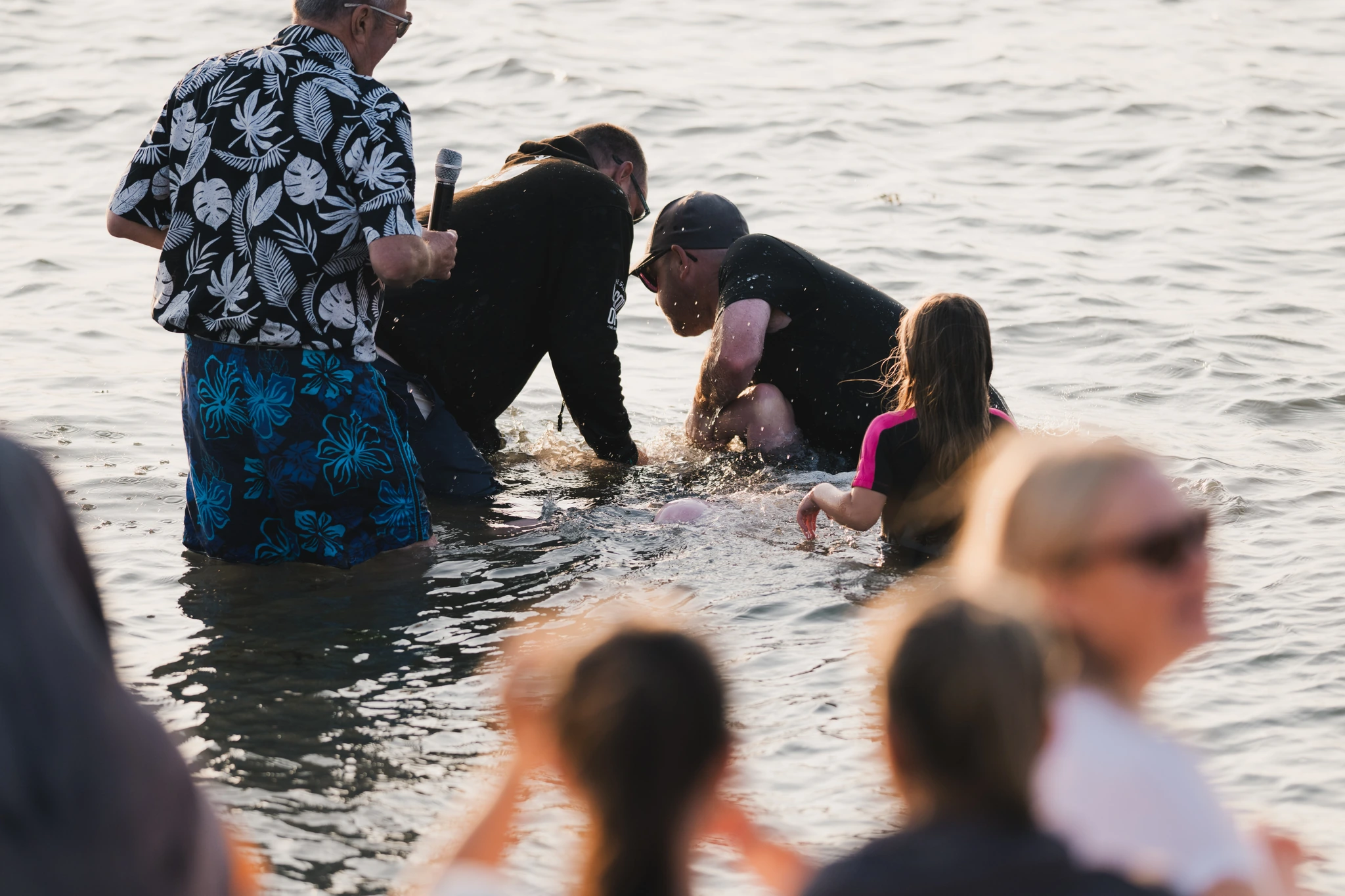 a group of people standing in the water with a baby in their lap