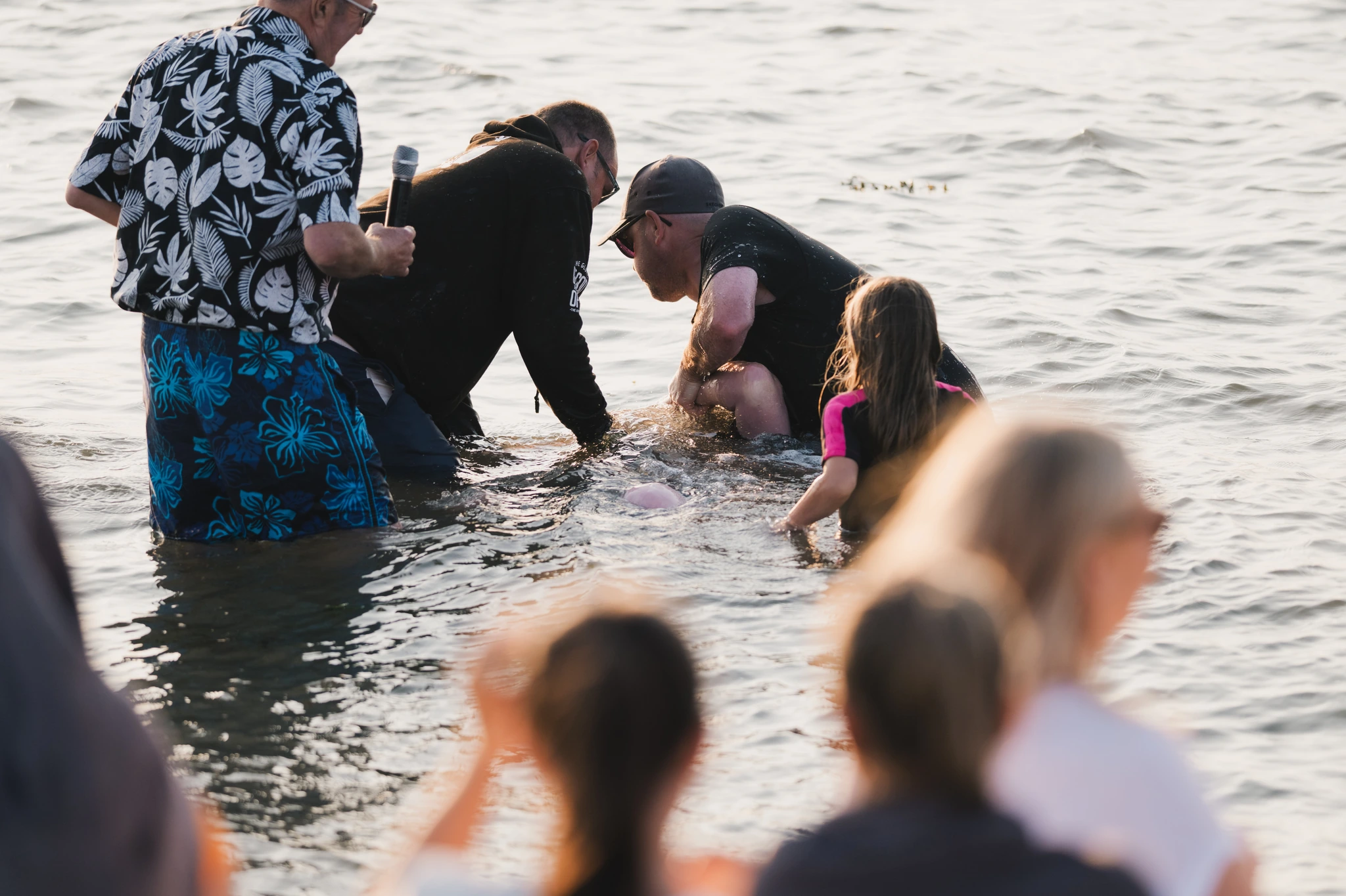 a group of people standing in the water with a baby in their lap