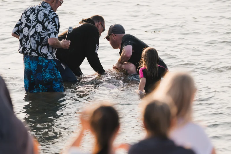 a group of people standing in the water with a baby in their lap