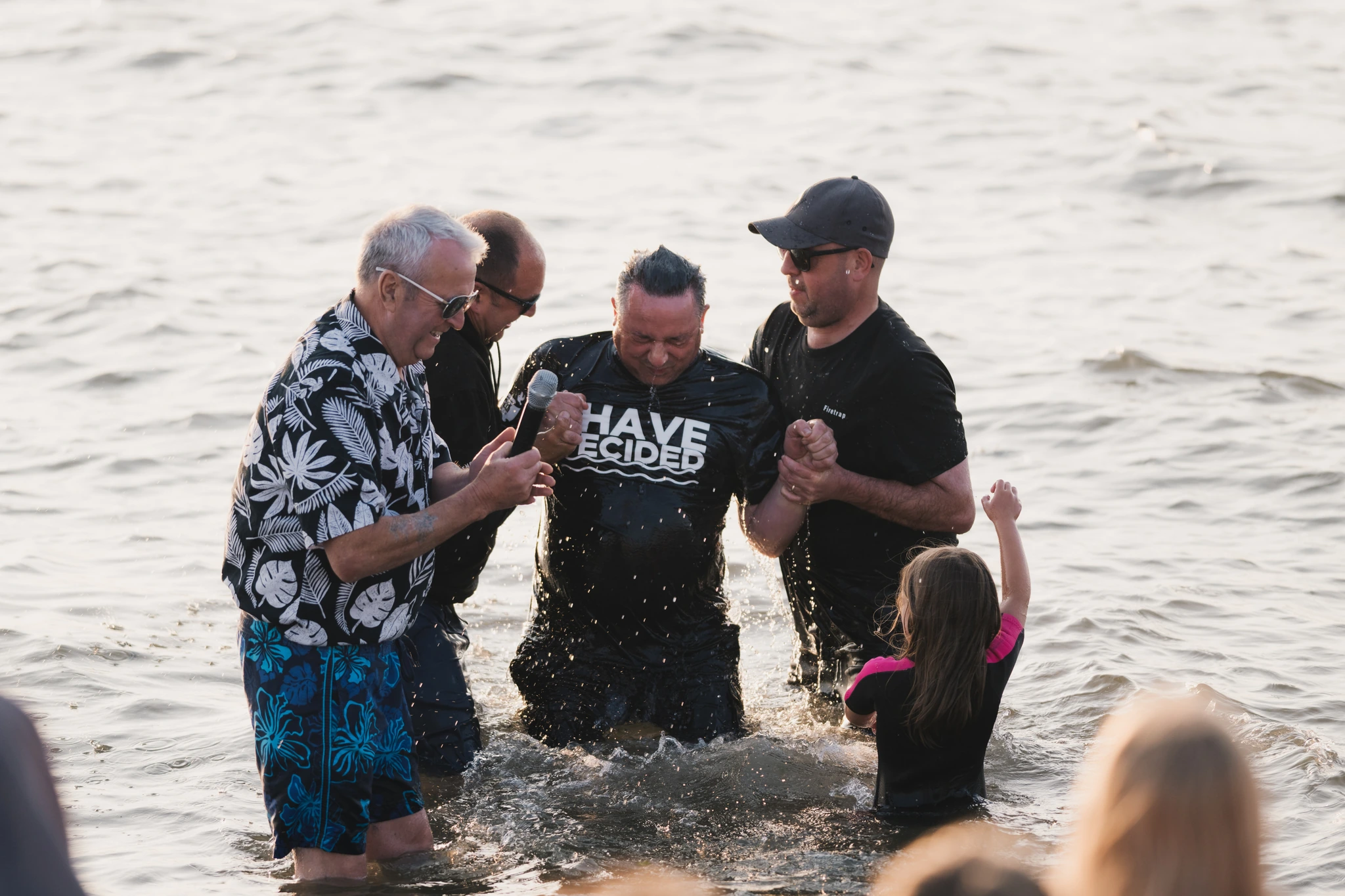 a group of people standing in the water with their hands in the air