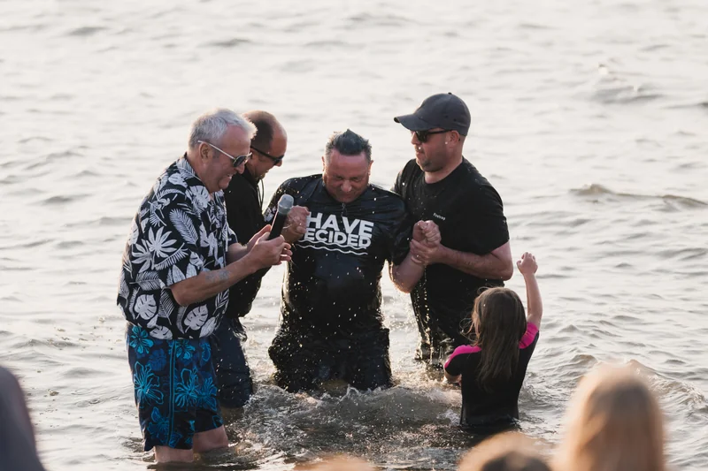 a group of people standing in the water with their hands in the air