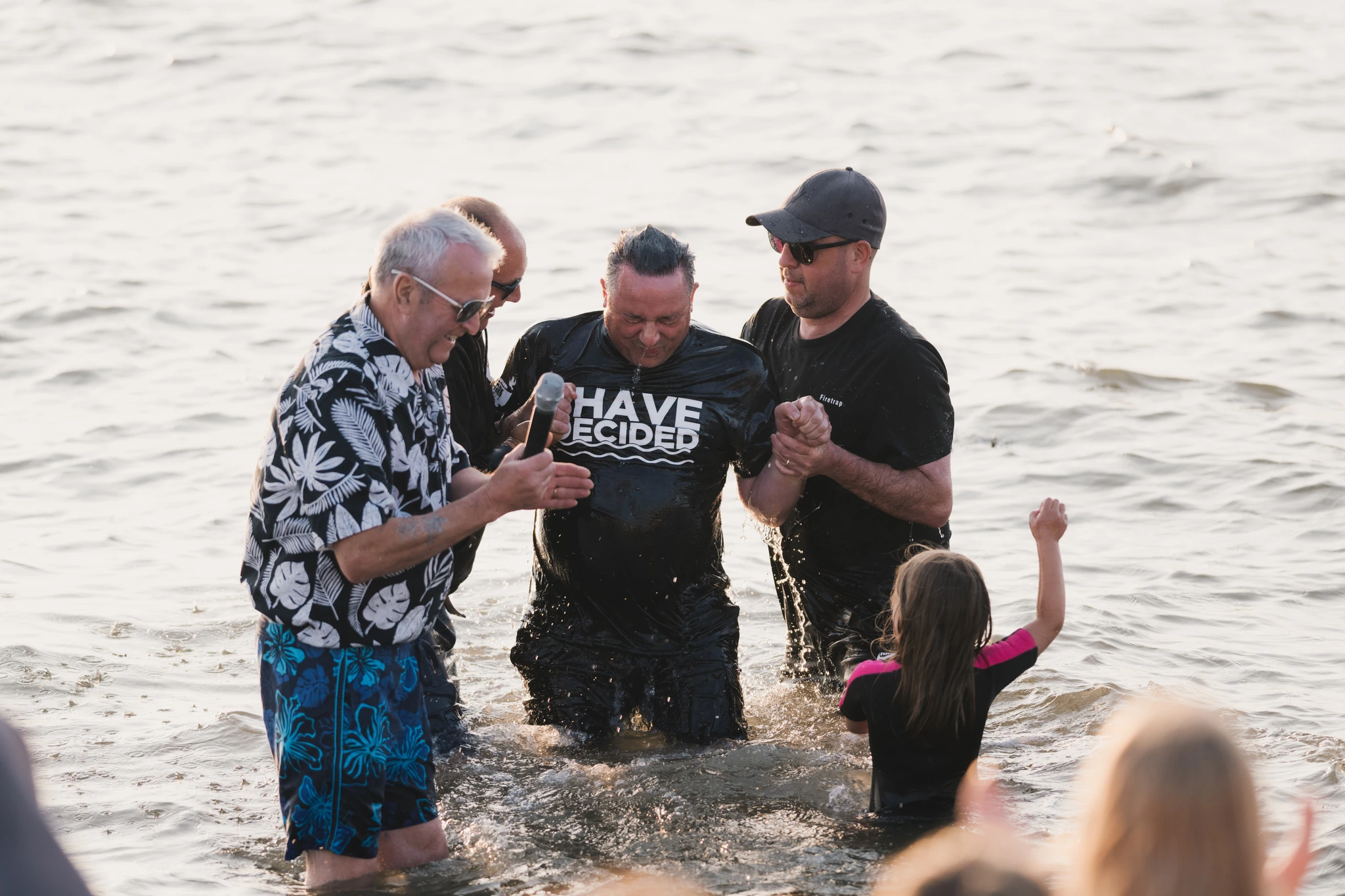 a group of people standing in the water with their hands in the air