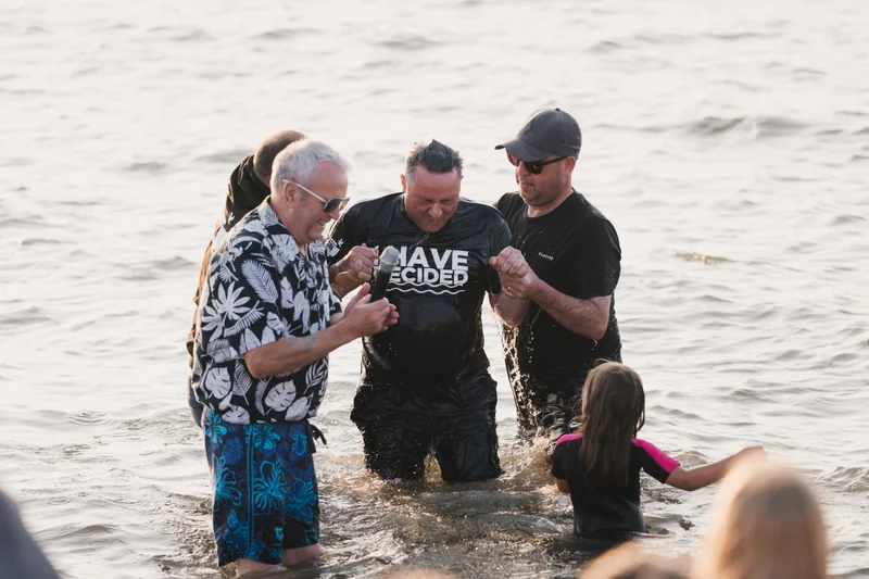 a group of people standing in the water with their hands in the air