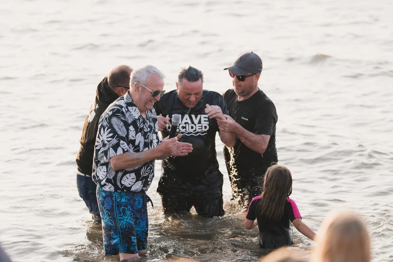a group of people standing in the water with their hands in the air