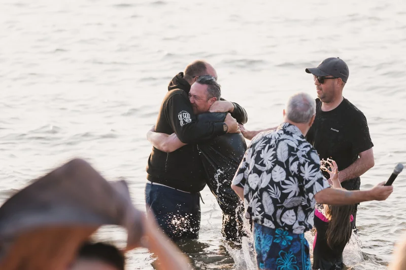 a man hugs another man in the water as he swims in the ocean