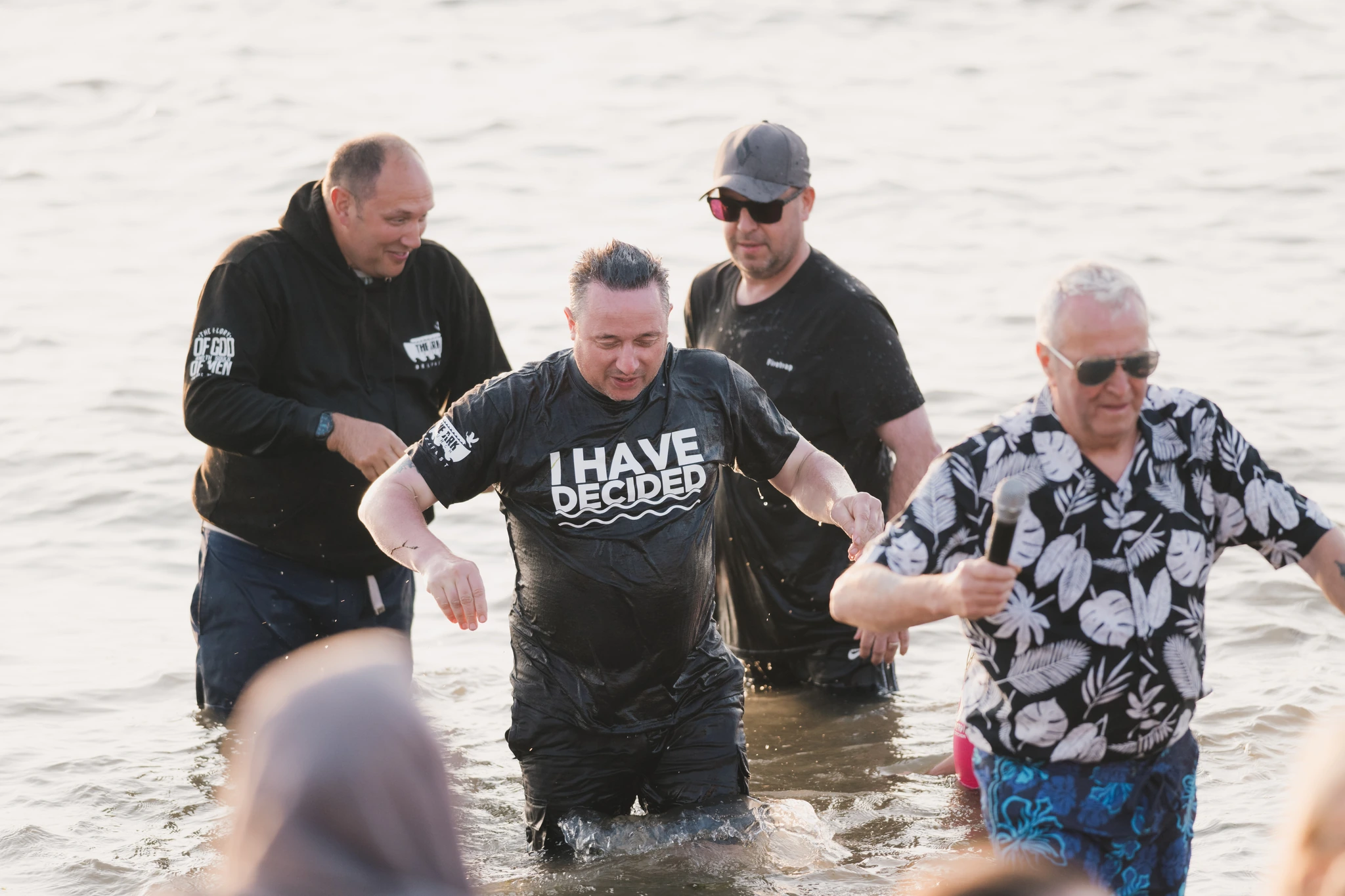 a group of people standing in the water with a sign saying i have faith