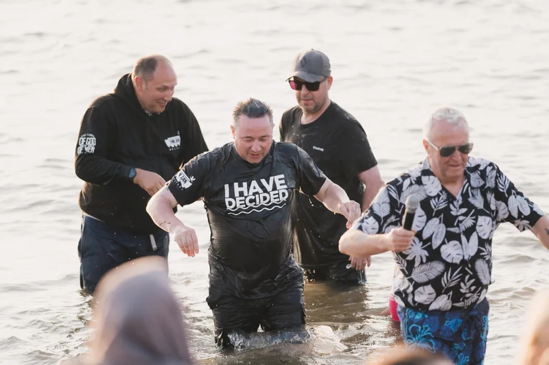 a group of people standing in the water with a sign saying i have faith