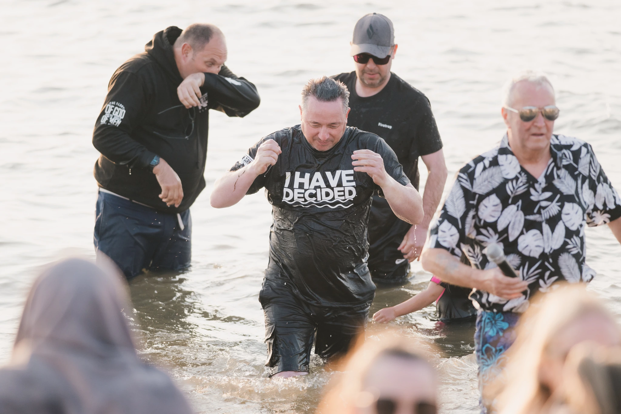 a group of people standing in the water at a baptism ceremony