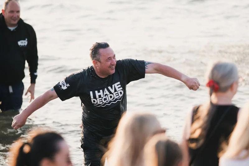 a group of people standing in the water with a sign saying i have faith