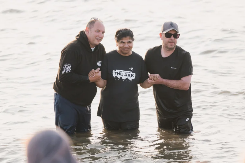 three men are standing in the water with their hands in the air