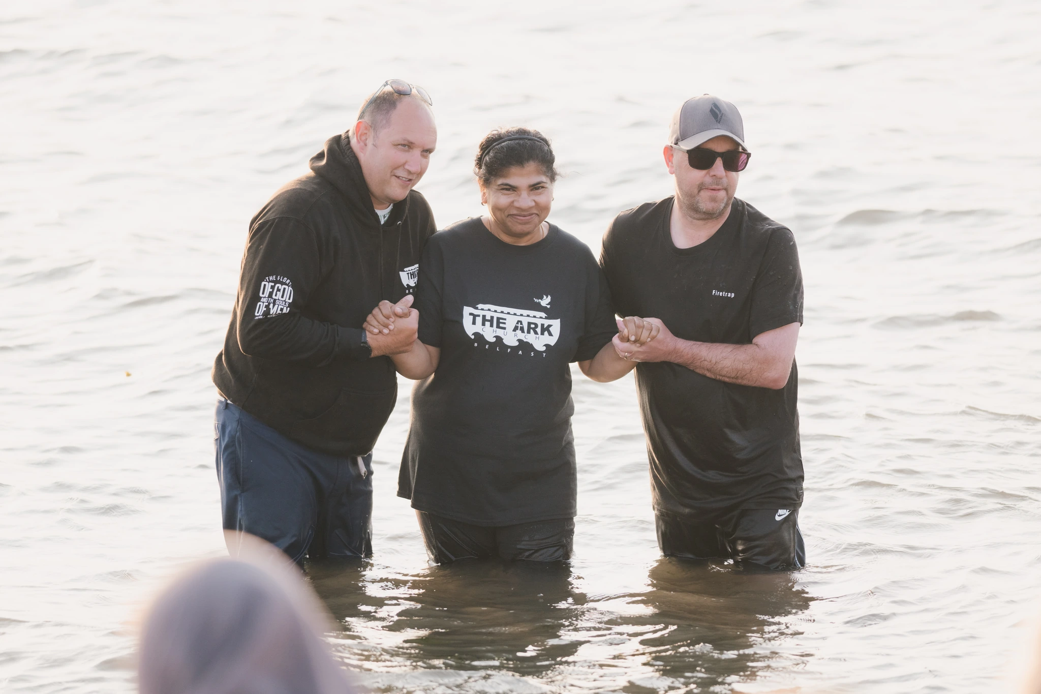 three men are standing in the water with their hands in the air