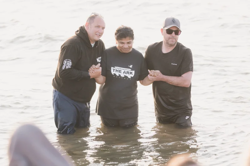 three men are standing in the water with their hands in the air