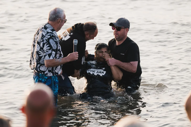 a man is being baptized in the water by a priest