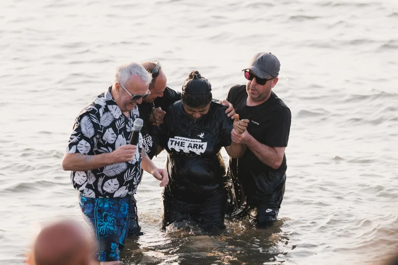 a group of people standing in the water with a man in front of them