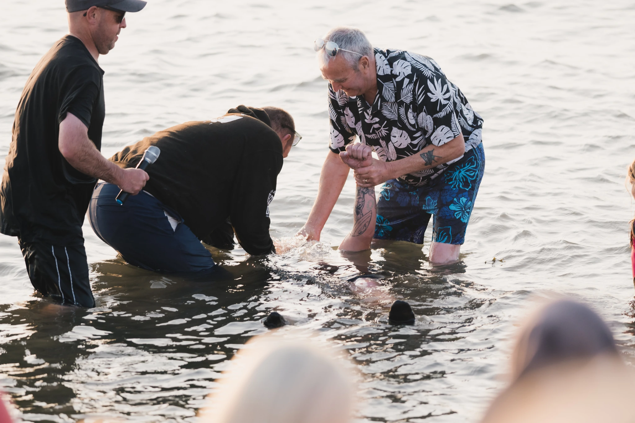 a group of people standing in the water with a man in front of them