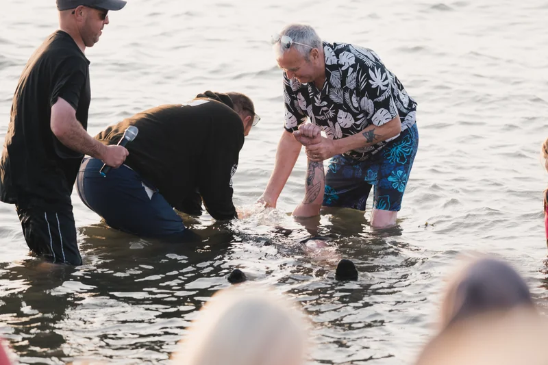 a group of people standing in the water with a man in front of them