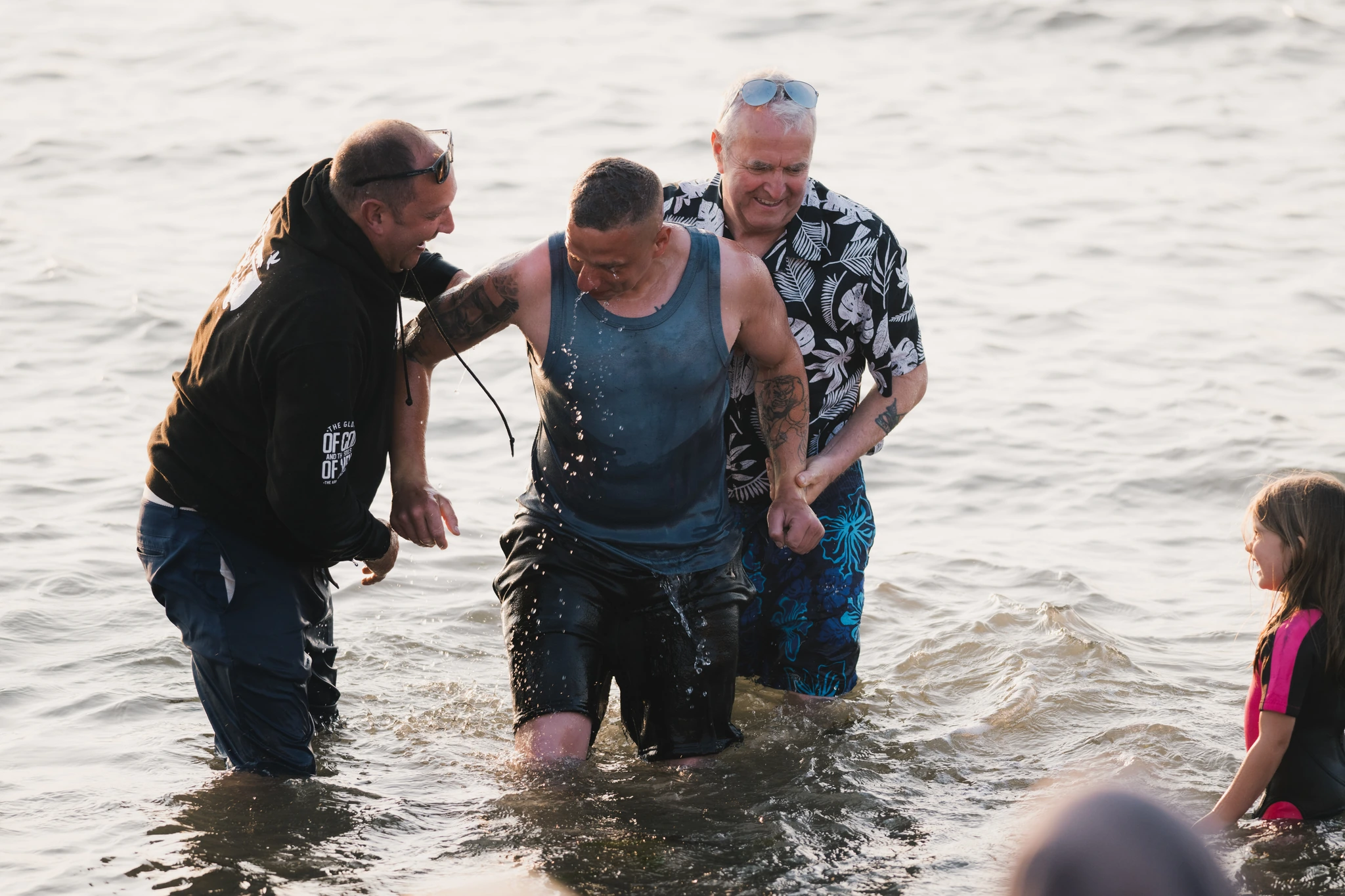 a group of people standing in the water with a man in front of them
