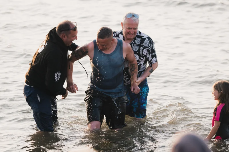 a group of people standing in the water with a man in front of them