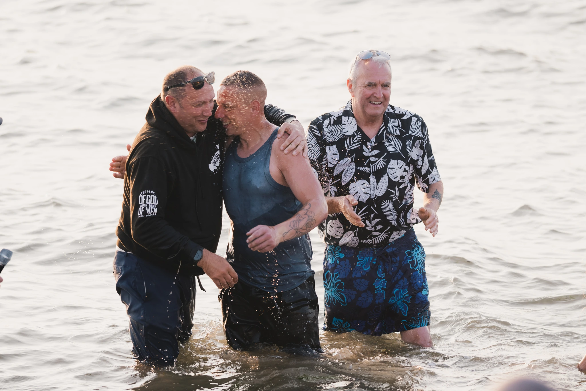 a group of men and women in the water at a baptism ceremony