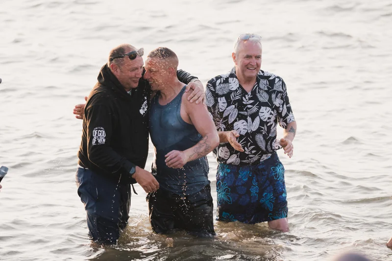 a group of men and women in the water at a baptism ceremony
