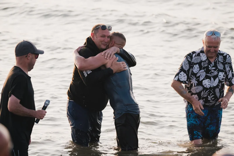 a man is embraced by another man in the water as he swims in the ocean