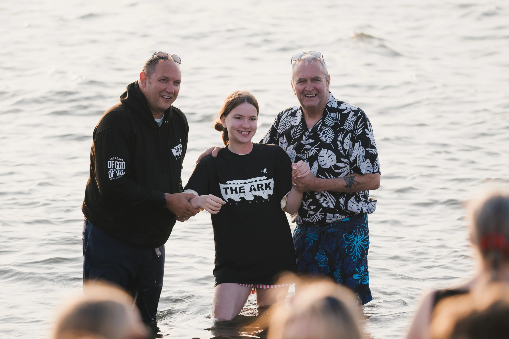 a group of people standing in the water with a man in front of them