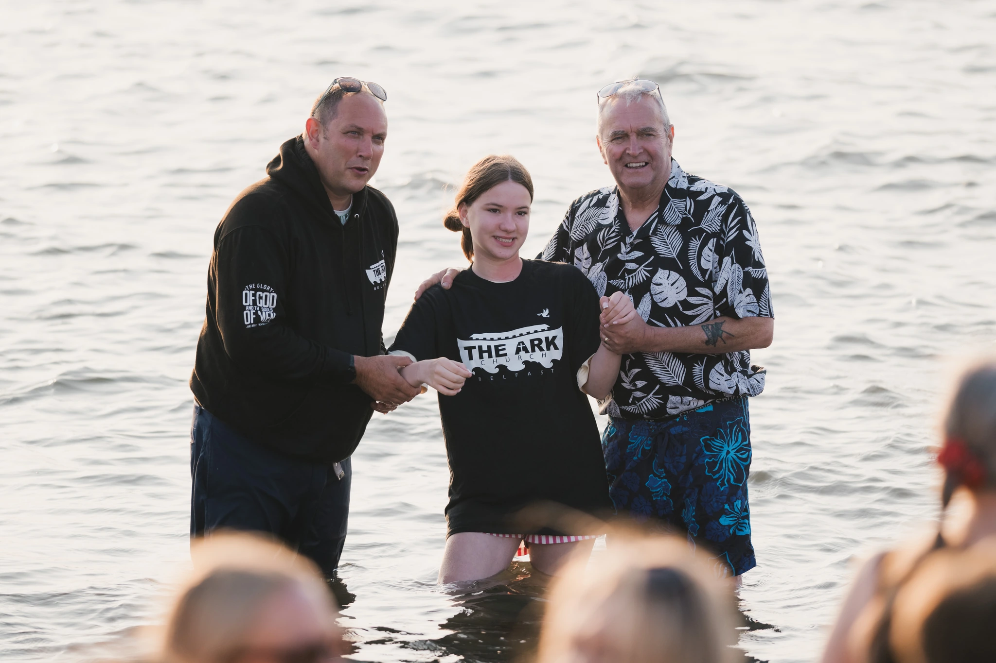 a man and woman standing in the water with their hands in the air