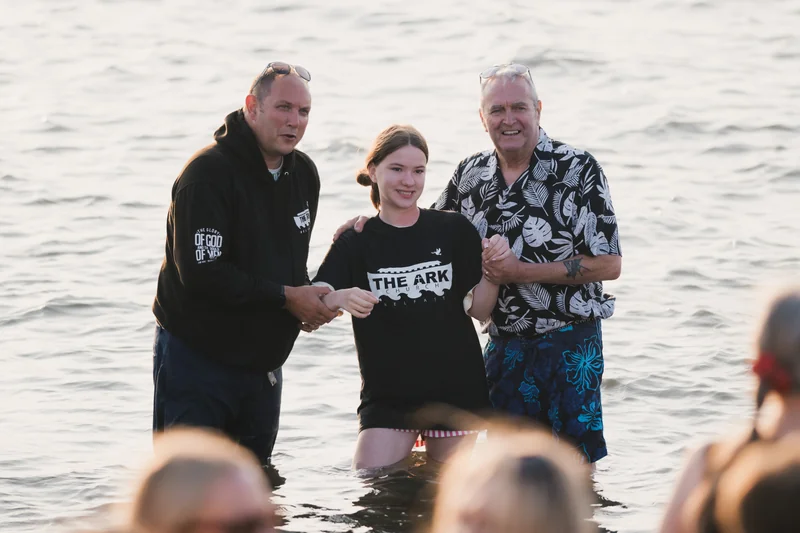 a man and woman standing in the water with their hands in the air