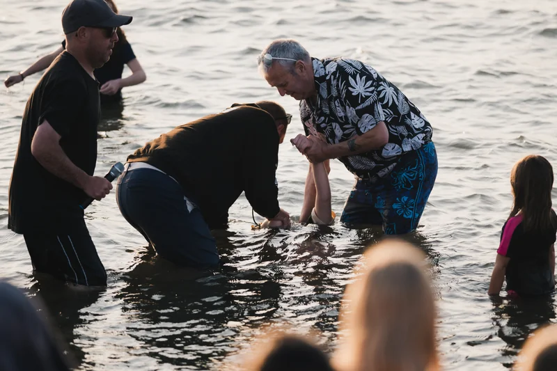 a group of people in the water at a baptism ceremony