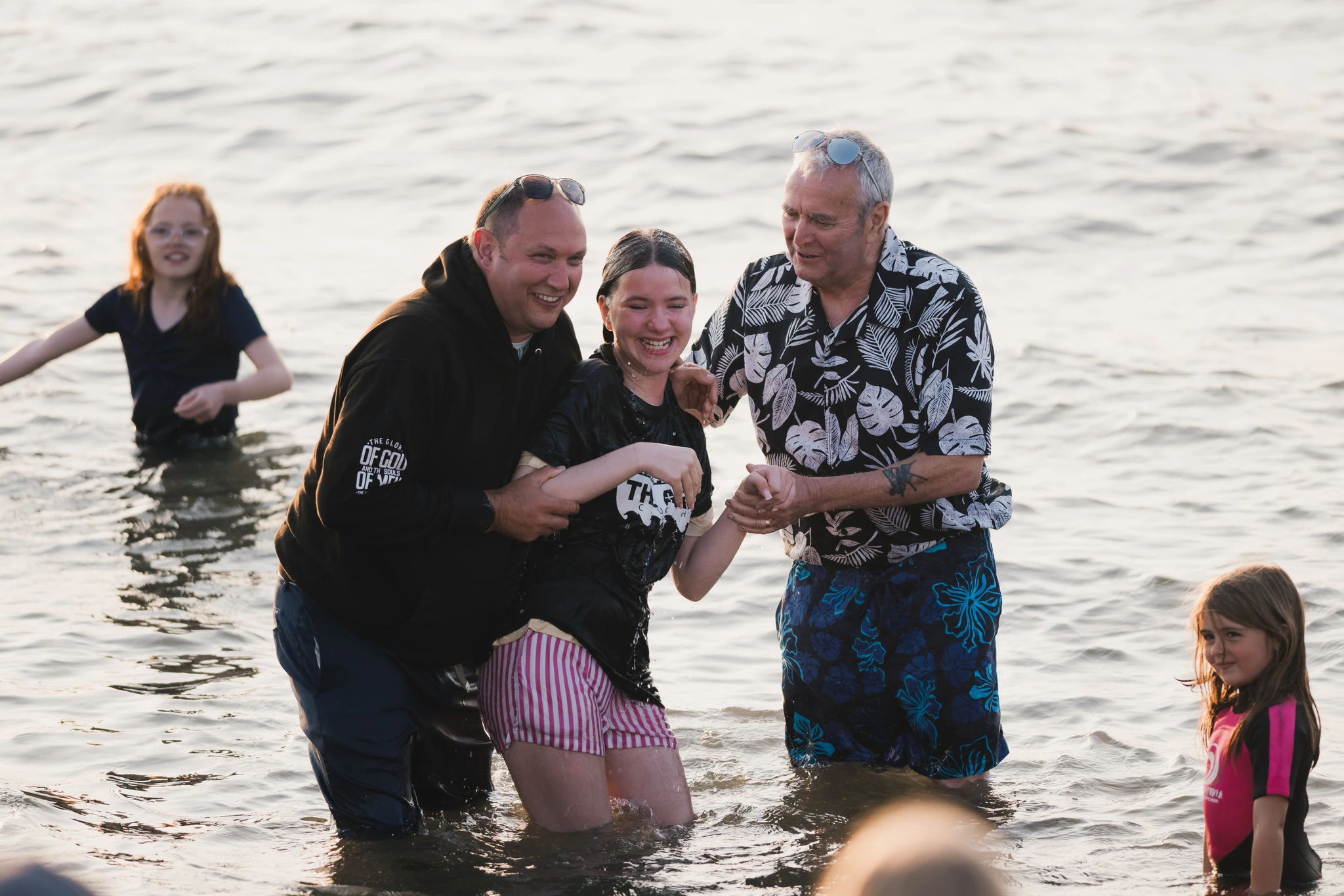 a group of people standing in the water with a man in the background