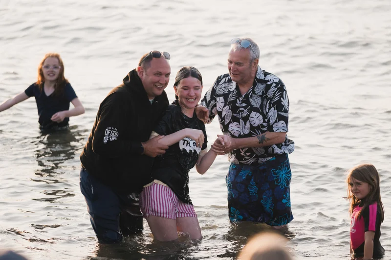 a group of people standing in the water with a man in the background