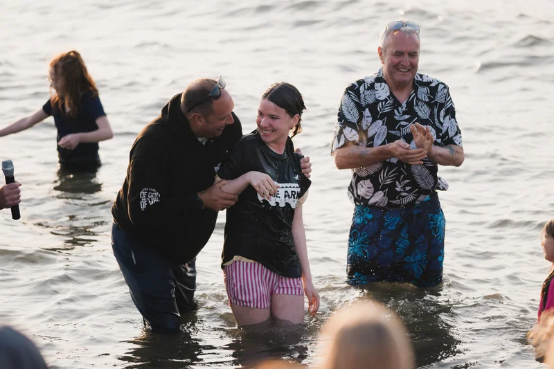 a group of people standing in the water with a man holding a woman