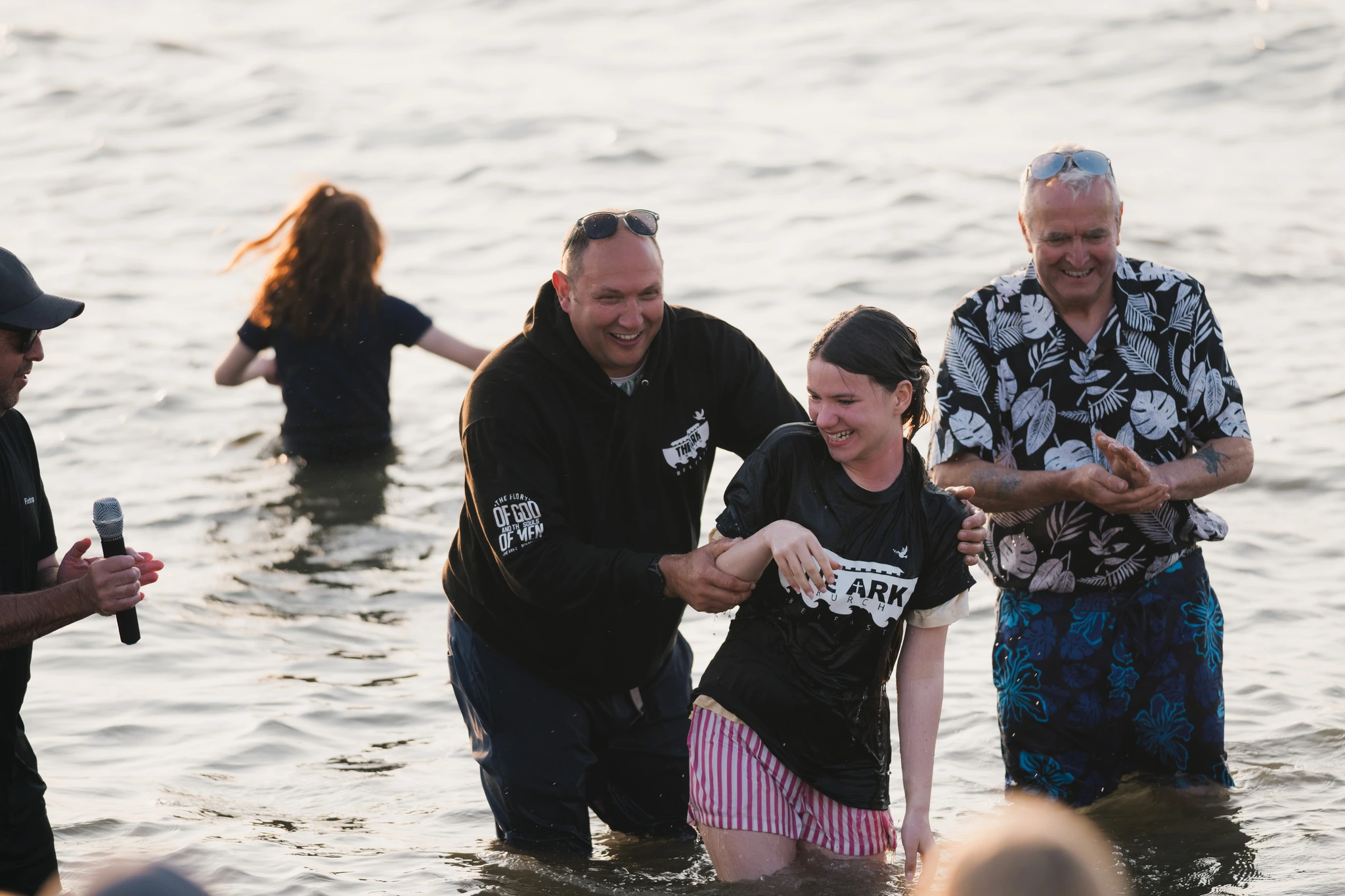 a group of people standing in the water with a man in the background