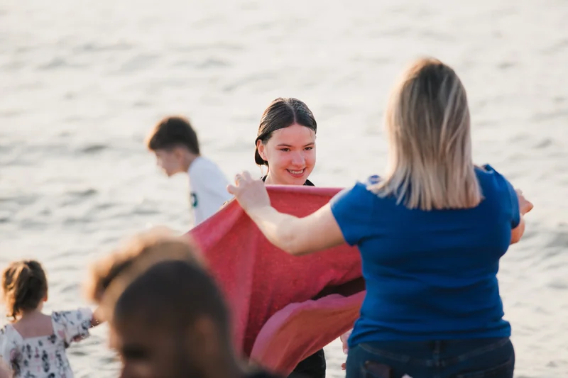 a girl is holding a towel on the beach in front of a group of people