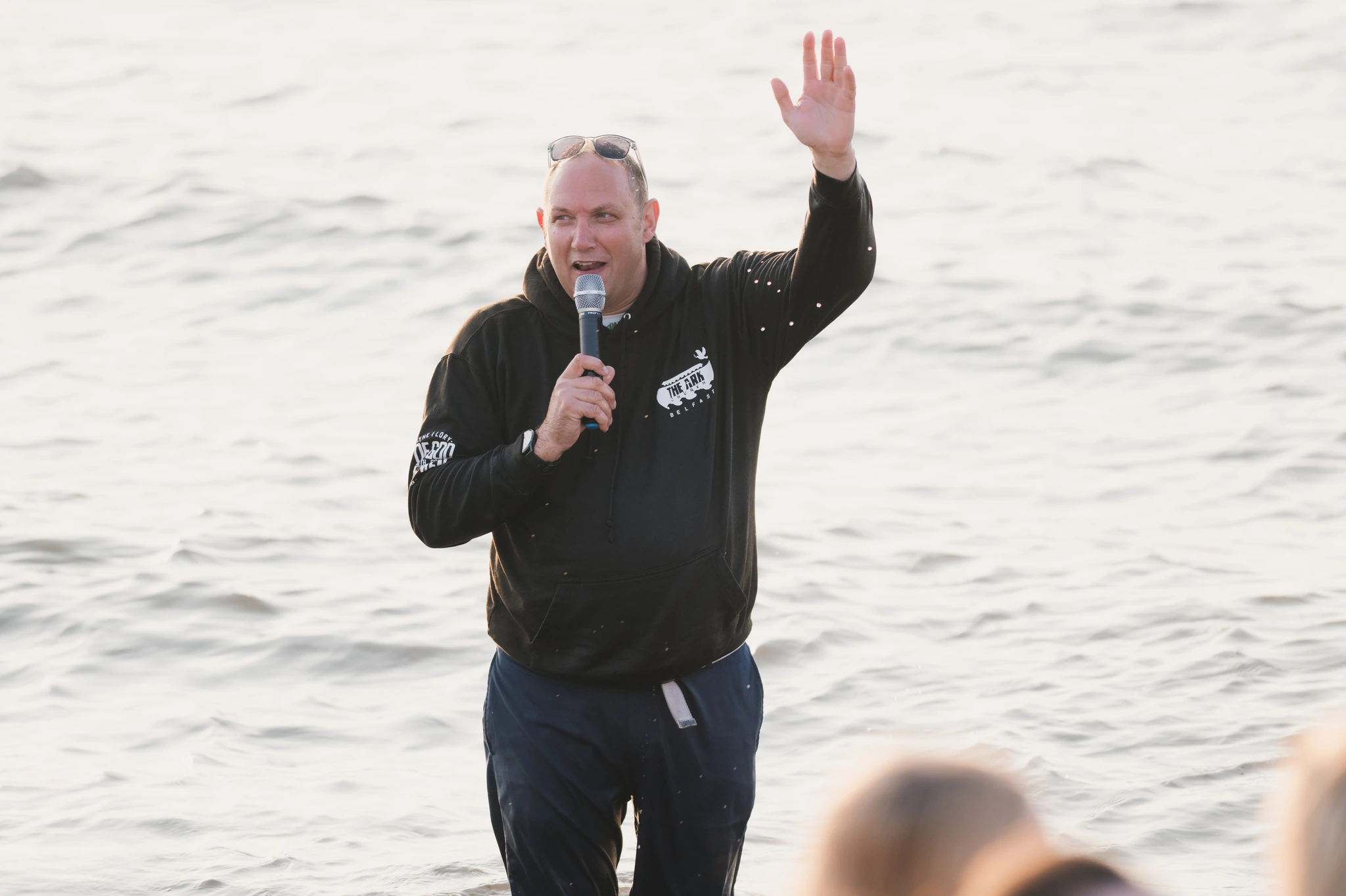 a man waving his hands in the air while standing in front of a group of people
