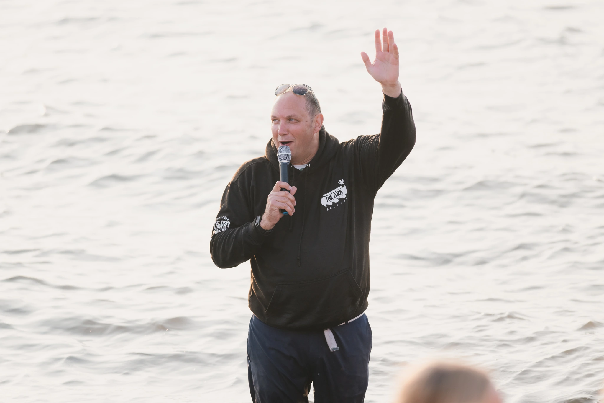 a man holding a microphone while waving his hands in the air