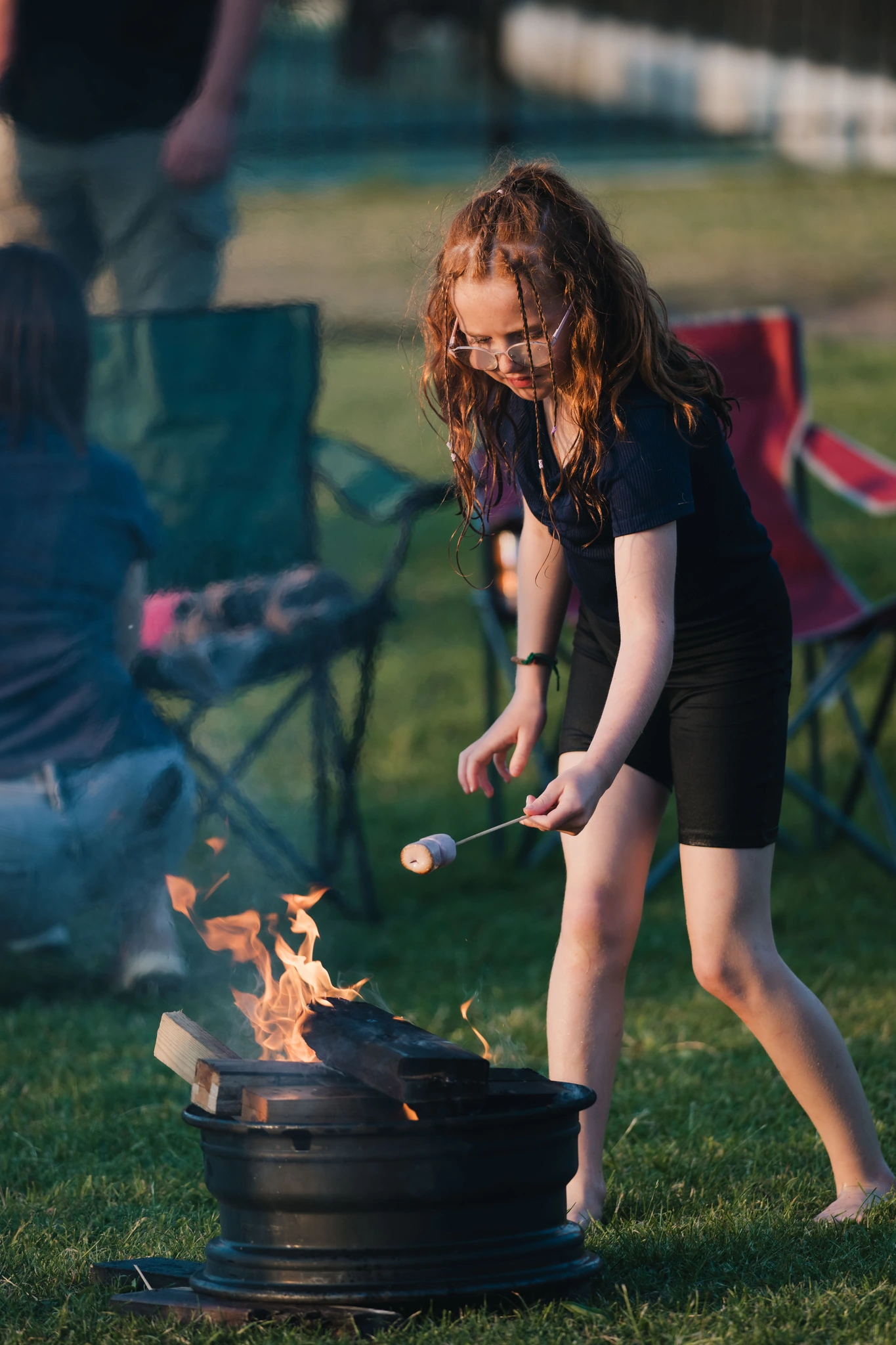 a little girl cooking on a campfire in a grassy field