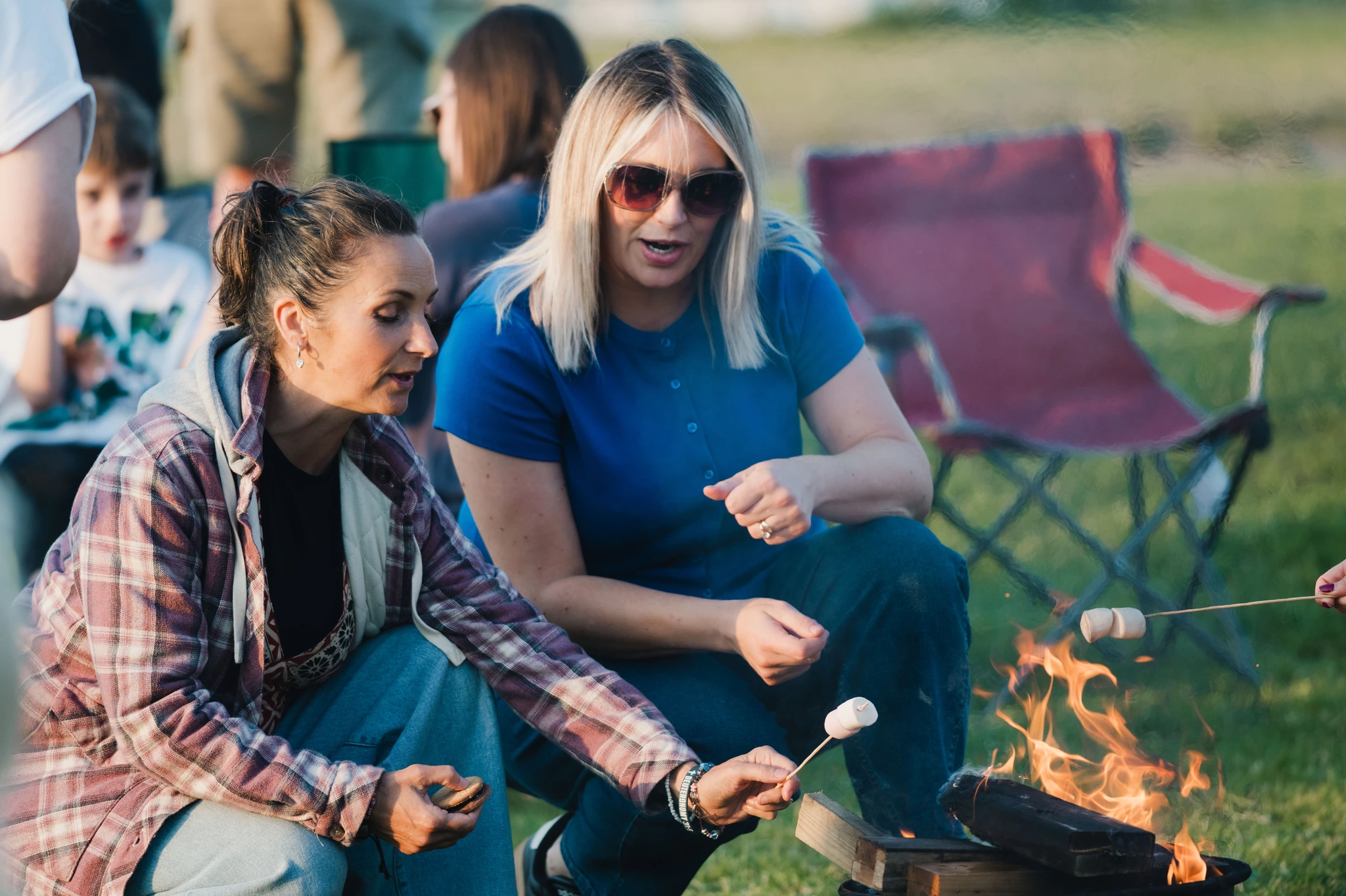 a group of people sitting around a campfire with marshmallows