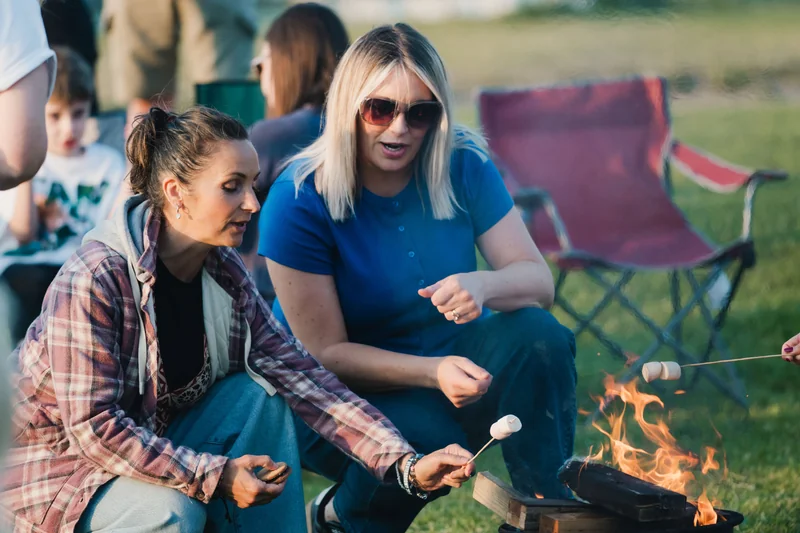 a group of people sitting around a campfire with marshmallows