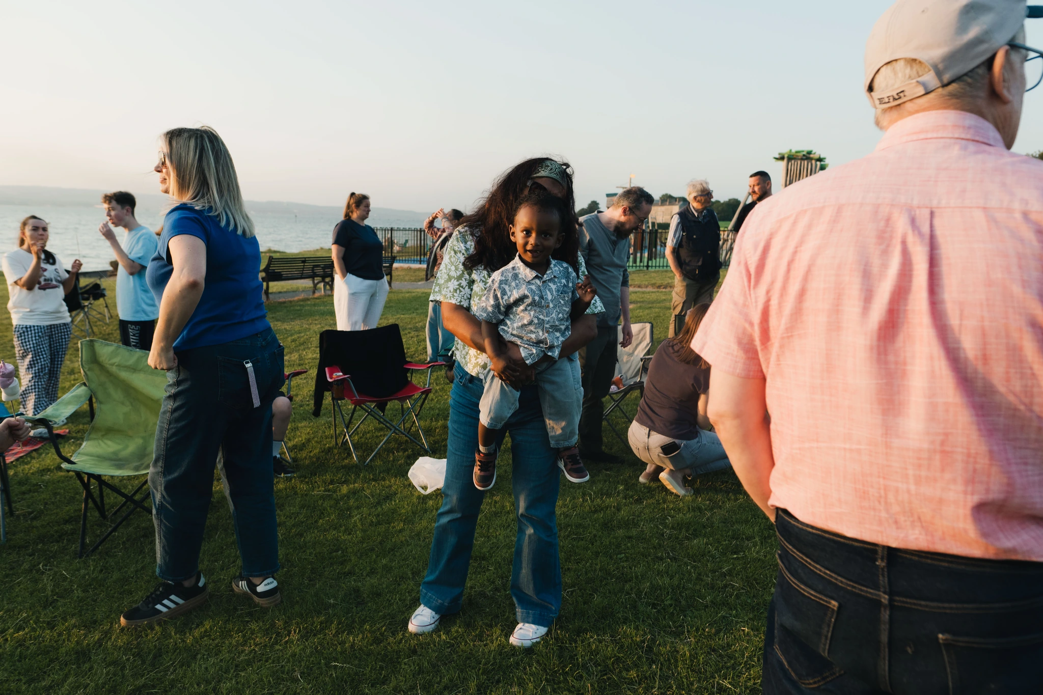 a group of people standing in a grassy field watching a sunset