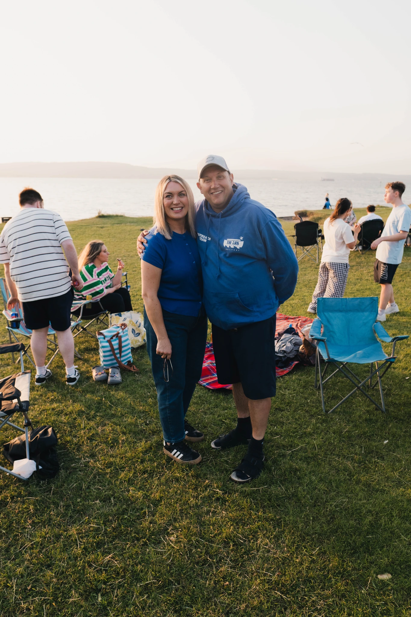 a man and woman standing in a grassy field at sunset