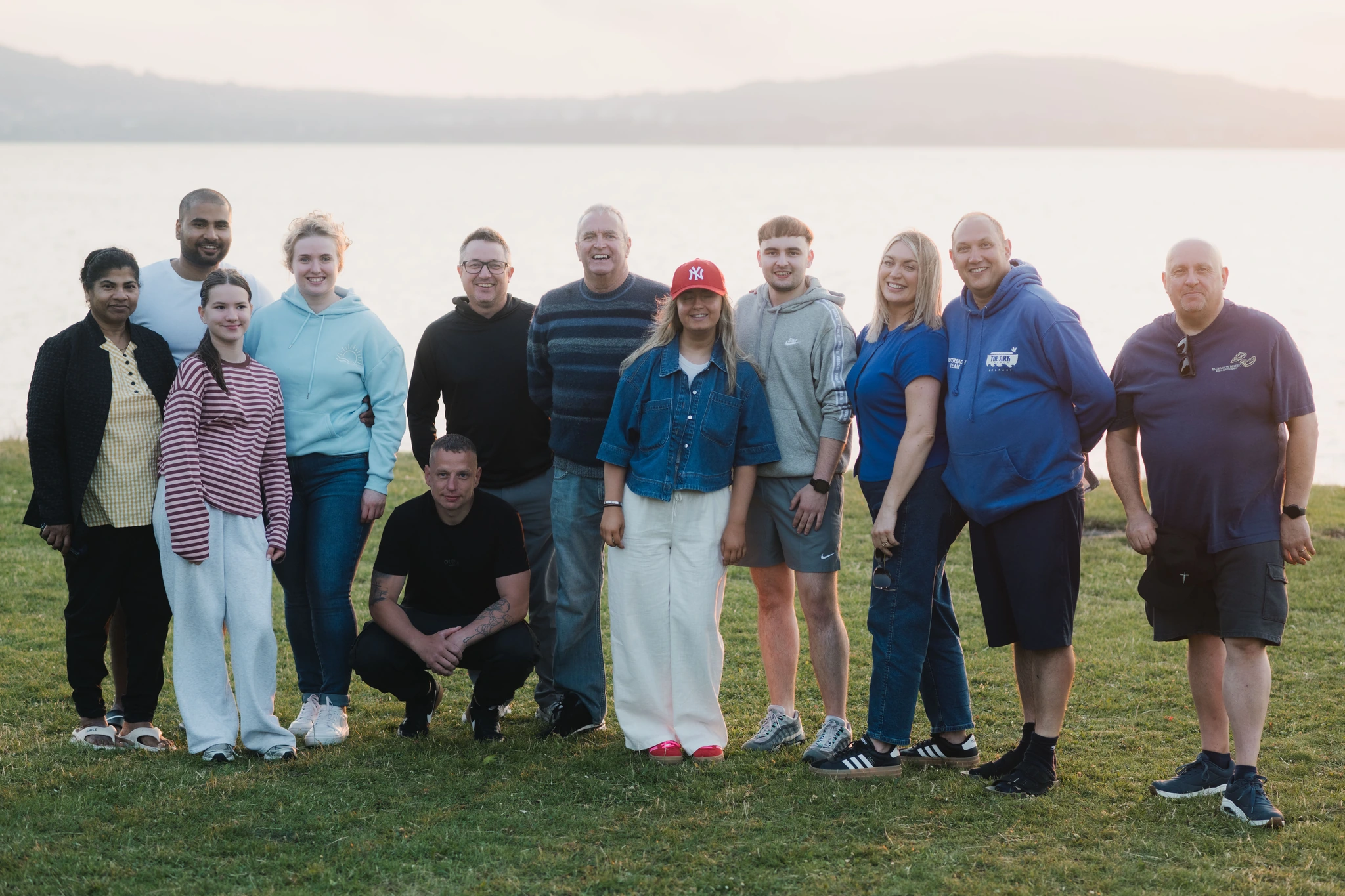 a group of people standing together in front of a lake