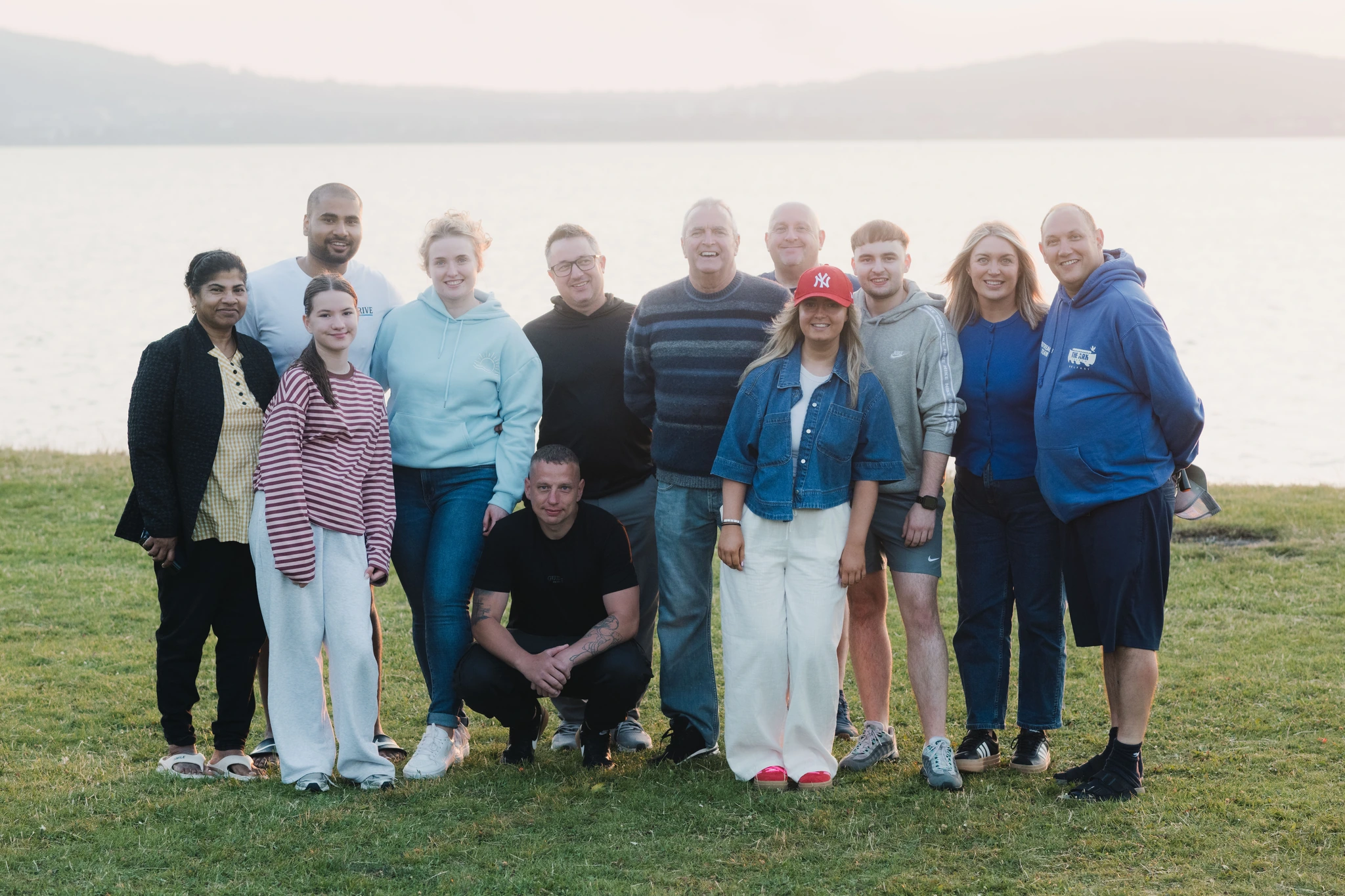 a group of people posing in front of a lake