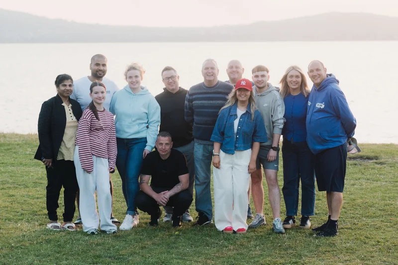 a group of people posing in front of a lake