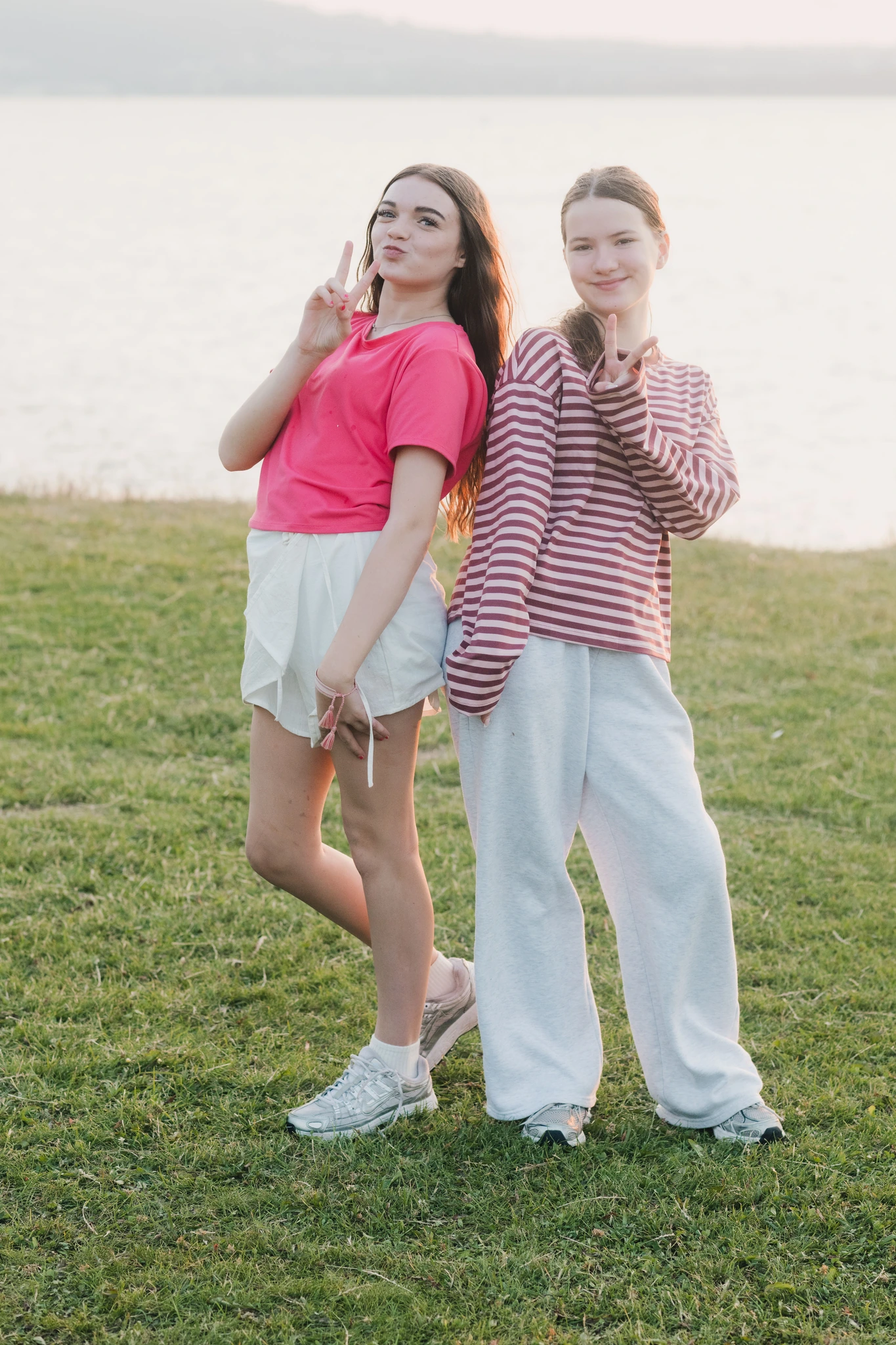two girls standing in front of a lake