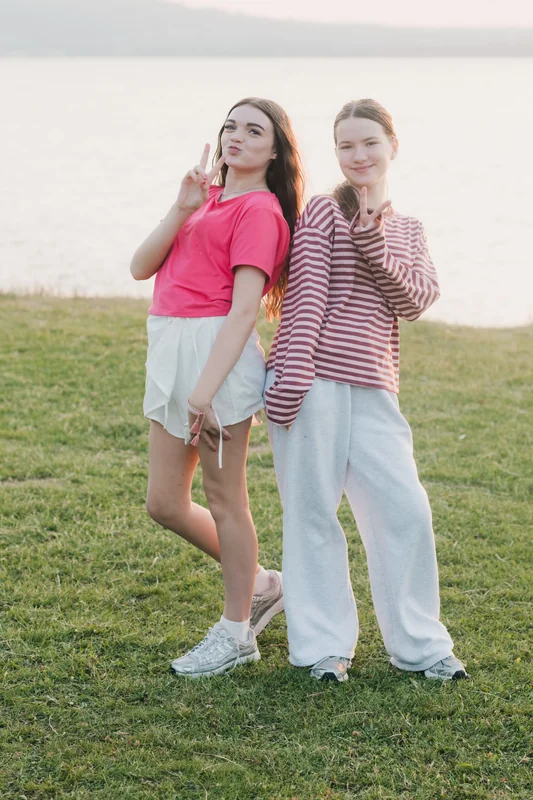 two girls standing in front of a lake
