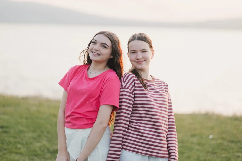 two girls posing in front of a lake